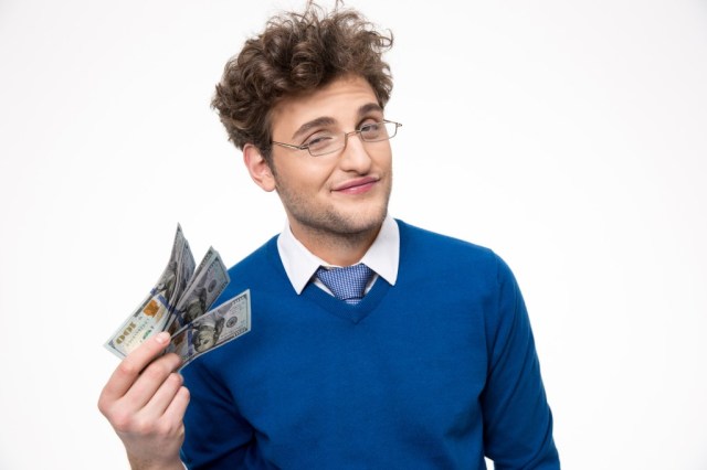 Happy businessman in glasses holding money over gray background